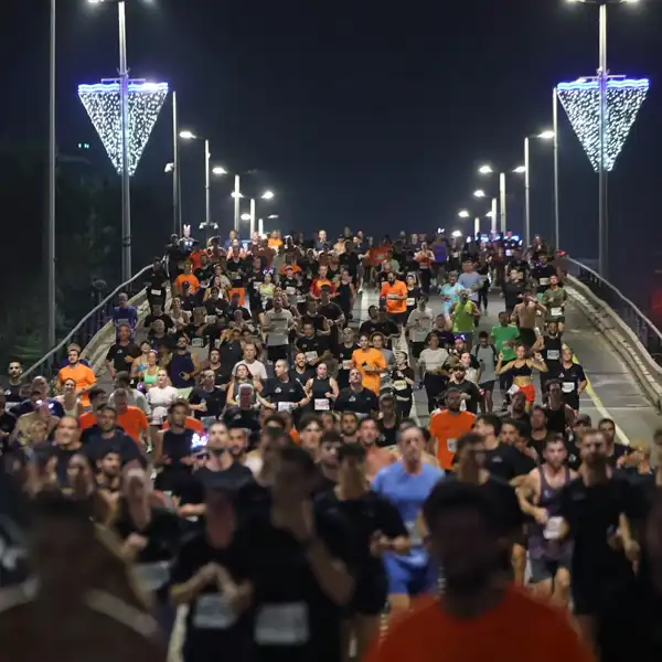 רצות ורצים על גשר מואר במסלול מרוץ הלילה תל־אביב