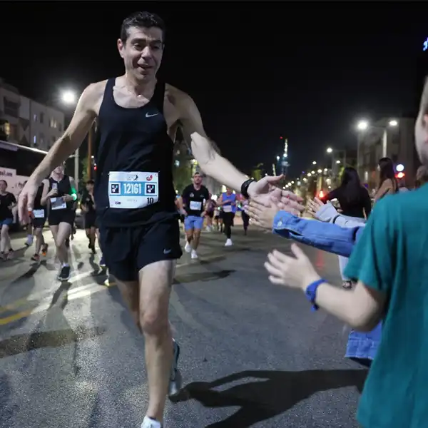 רץ מקבל כיף מילדים לאורך מסלול מרוץ הלילה תל־אביב